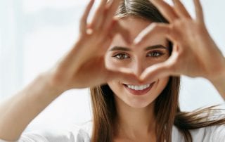 Woman Making Heart Sign with Hands Over her Eyes