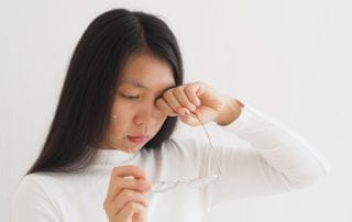 Girl Holding Glasses While Rubbing Eye